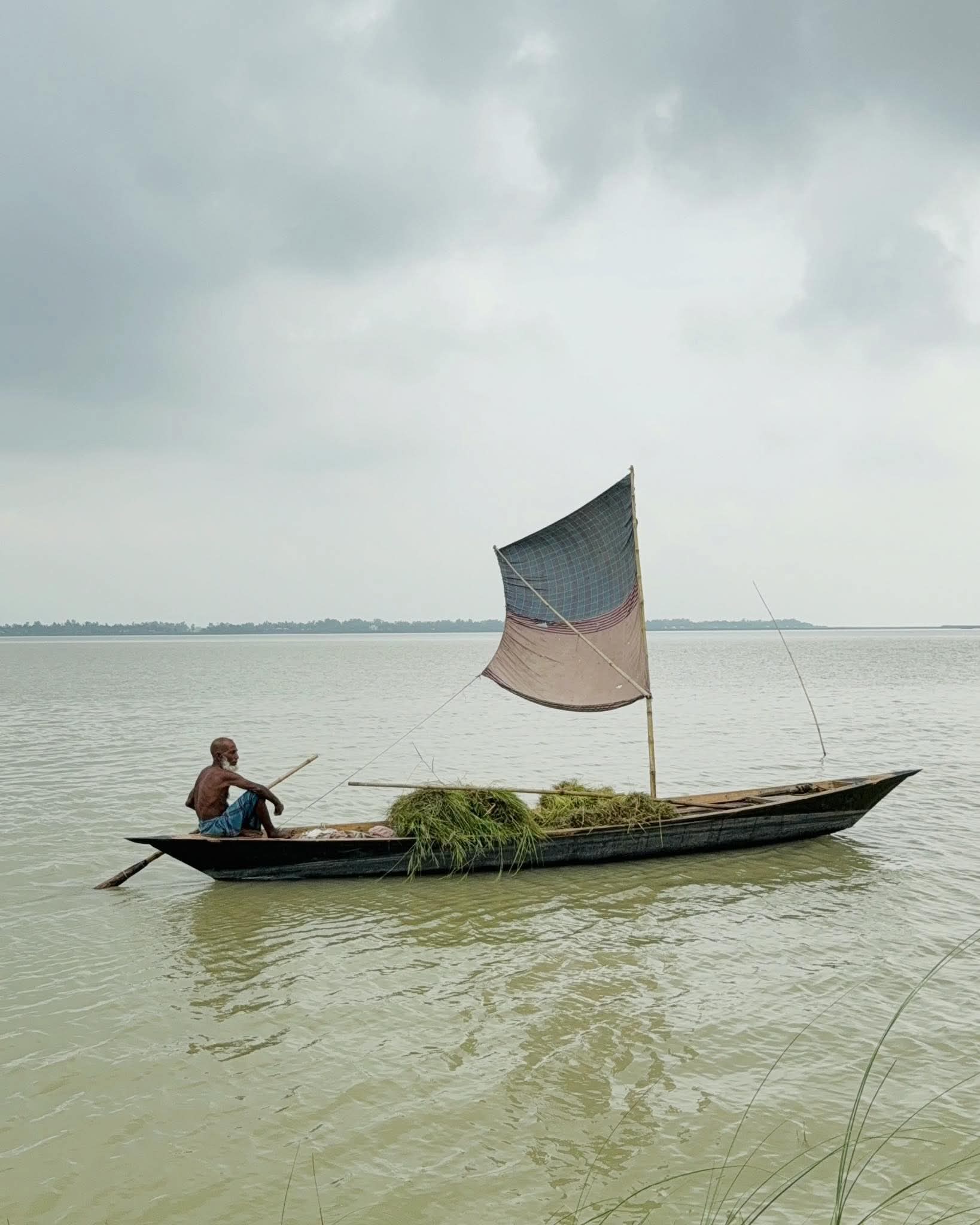 নদীতে পাল তোলা নৌকা বয়ে নিয়ে যাচ্ছে মাঝি। নদীতে পাল তোলা নৌকা ছবি।